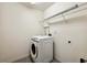 Bright laundry room with a white washer, wire shelving, and gray tile flooring at 11434 Wishing Well Ln, Clermont, FL 34711