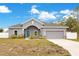 Gray house with a two-car garage and landscaped front yard at 2011 Begonia Way, Poinciana, FL 34759