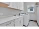 Bright laundry room features white cabinetry, countertop with sink, and modern washer at 247 Hampton Loop, Davenport, FL 33837