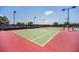 Well-maintained community tennis court with green and red surface and lighting at 247 Hampton Loop, Davenport, FL 33837