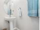 Charming half bathroom featuring a pedestal sink, elegant oval mirror, and stylish towel selection at 5381 Via Appia Way, Sanford, FL 32771