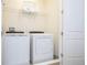 A bright laundry room featuring a white washer and dryer with a wire rack and white basket at 7600 Mackinaw Ln, Kissimmee, FL 34747