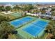 Aerial view of community tennis courts surrounded by lush greenery and palm trees in a Gathering friendly neighborhood at 7600 Mackinaw Ln, Kissimmee, FL 34747