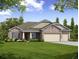 One-story home with stone and shingle accents, three-car garage, and landscaped lawn at Tbd Palm Ave, Leesburg, FL 34748