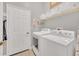 Neat laundry room with white washer and dryer, overhead storage, and access door at 1012 Everest St, Clermont, FL 34711