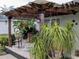 Relaxing patio space with pergola cover, lush landscaping, and comfortable seating at 124 Hollyhock Ct, Kissimmee, FL 34743