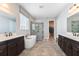 Bathroom featuring a soaking tub, glass-enclosed shower, dual sinks with dark cabinetry, and a walk-in closet at 13596 Gorgona Isle Dr, Windermere, FL 34786