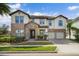 Beautiful two-story home featuring a combination of stone and stucco, a tile roof, and a well-manicured lawn at 13596 Gorgona Isle Dr, Windermere, FL 34786