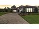 Home exterior with a brick driveway, manicured landscaping, and gray tiled roof at sunset at 25974 High Hampton Cir, Sorrento, FL 32776