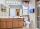 Well-lit bathroom featuring double sinks, a toilet, and a glass-door shower at 2632 Sand Hill Point Cir, Davenport, FL 33837