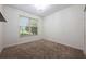 Vacant room boasts neutral walls, plush carpet, a window, and a chandelier at 3966 Avalon Park West Blvd, Orlando, FL 32828