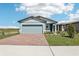 Charming single-story home with a two-car garage, a brick-paved driveway, and a beautifully manicured front yard at 4027 Copperleaf Ln, Poinciana, FL 34759