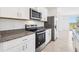 Modern kitchen with stainless steel appliances, granite counters, and white cabinetry at 4027 Copperleaf Ln, Poinciana, FL 34759