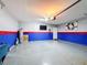 View of the epoxy-floor finished garage with painted blue and red accent walls, plus a wall mounted TV at 651 Tortugas St, Haines City, FL 33844