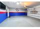 View of the epoxy-floor finished garage with painted blue and red accent walls, plus a wall mounted TV at 651 Tortugas St, Haines City, FL 33844