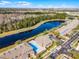 An aerial view of a complex featuring a pool, water views, manicured lawns, and dedicated parking at 10421 Manderley Way # 268, Orlando, FL 32829