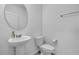 Clean powder room with a pedestal sink, round mirror, toilet, and towel bar at 12043 Holystone St, Winter Garden, FL 34787