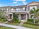 Charming townhouse exterior featuring lush landscaping, a covered entryway, and multiple windows at 16521 Prairie School Dr, Winter Garden, FL 34787
