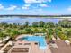 Aerial view of a community pool with lounge chairs, palm trees, and a stunning lake view at 16521 Prairie School Dr, Winter Garden, FL 34787