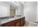 Bathroom with wood cabinets, granite counters, single sink, mirror, and walk-in shower at 17438 Promenade Dr, Clermont, FL 34711