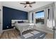 Comfortable bedroom with a large window, blue accent wall, and wood-look flooring at 17438 Promenade Dr, Clermont, FL 34711