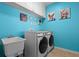 Bright laundry room with blue walls, artwork, washer, dryer, and utility sink at 17438 Promenade Dr, Clermont, FL 34711