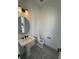 Small bathroom with pedestal sink, round mirror, and gray tile floors at 2118 Whitney Marsh Aly, Orlando, FL 32804