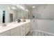 Bright bathroom featuring double sinks, large mirrors, walk-in shower with glass door, and decorative tile floor at 2351 Fenton Ave, Clermont, FL 34711