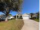 Charming single-story home featuring a well-manicured lawn, mature trees, and a two-car garage at 2351 Fenton Ave, Clermont, FL 34711