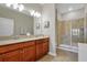 Bathroom with dual sinks, wood cabinets, a neutral color scheme, a large mirror, and a walk-in shower at 3525 Belland Cir # A, Clermont, FL 34711