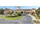 Beautiful clubhouse entrance with a circular driveway, lush landscaping, and a welcoming water fountain feature at 3525 Belland Cir # A, Clermont, FL 34711