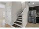 Staircase leading upstairs, adjacent to a stainless steel refrigerator and a doorway to another room at 3610 Charmed Ln, St Cloud, FL 34772