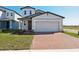 Charming two-story home featuring a gray exterior, a brick driveway, and a well-manicured lawn at 4026 Copperleaf Ln, Poinciana, FL 34759