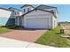 Attractive house featuring a gray exterior, a brick driveway, and a well-maintained lawn at 4026 Copperleaf Ln, Poinciana, FL 34759