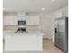 Bright, modern kitchen features white cabinetry, stainless steel appliances, and a large island with a sink at 4026 Copperleaf Ln, Poinciana, FL 34759