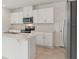 Bright kitchen featuring white cabinets, stainless steel appliances, and an island with quartz countertop at 4026 Copperleaf Ln, Poinciana, FL 34759