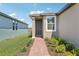 Inviting front entrance with a well-manicured garden, brick pathway and contemporary door at 4031 Cooperleaf Ln, Poinciana, FL 34759