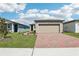 Charming single-Gathering home featuring a brick driveway, two car garage and manicured lawn at 4031 Cooperleaf Ln, Poinciana, FL 34759