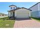 Charming two-story home with a brick driveway and a two-car garage, surrounded by a well-manicured lawn at 4034 Copperleaf Ln, Poinciana, FL 34759