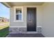 A close-up of the front door with a small window to the side, surrounded by stone and brick accents at 4034 Copperleaf Ln, Poinciana, FL 34759