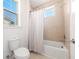 Bright bathroom features a shower over tub combination, window and white shower curtain at 10231 Beechwood Ln, Orlando, FL 32832