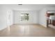 Open living area with tile flooring, white walls, a large window, and an adjacent kitchen area at 10305 Licorice Way, Orlando, FL 32821
