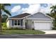 Charming single-Gathering home with gray siding, stone accents, a two-car garage, and a manicured front lawn at 1204 White Ash Loop, Deland, FL 32720