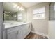 Bright bathroom featuring dual sinks, a large mirror, a walk-in shower, and stylish wood-look floors at 1217 E Muriel St, Orlando, FL 32806