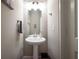 A half bathroom with a pedestal sink and a decorative mirror on a light, neutral wall at 1217 E Muriel St, Orlando, FL 32806