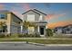 A gray two-story home with manicured lawn, green door, and small front porch with seating at 2429 Volunteer Ave, Kissimmee, FL 34744