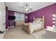 Bedroom showcasing vibrant purple walls, a large bed, dresser, and makeup vanity at 2438 River Rise Ct, Orlando, FL 32828