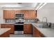 Well-lit kitchen featuring stainless steel appliances, granite counters, tile backsplash and stylish wood cabinetry at 309 Oakwood Ct, Lake Mary, FL 32746