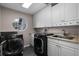 Functional laundry room features washer, dryer, sink, storage cabinets and a round window at 309 Oakwood Ct, Lake Mary, FL 32746