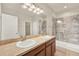 Well-lit bathroom featuring double sinks, large mirrors, and a marbled shower at 3773 Moon Dancer Pl, St Cloud, FL 34772